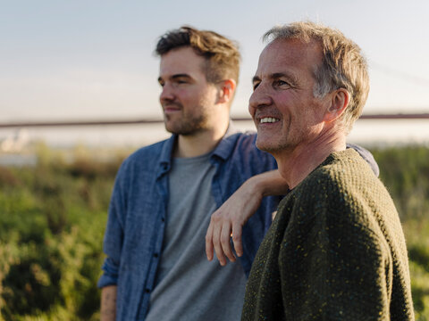 Thoughtful father and son looking at riverbank
