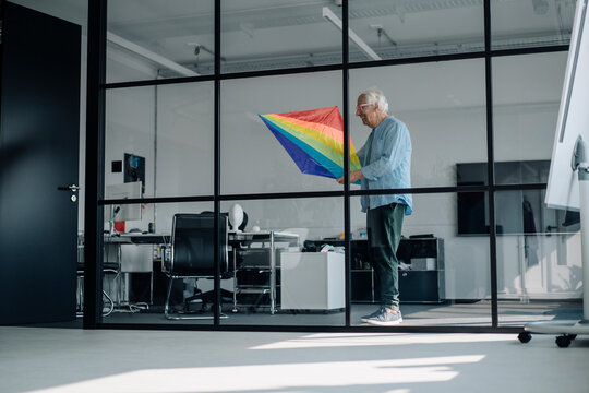 Businessman holding multi colored kite while standing in office
