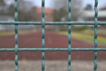 close-up of a metal fence in front of a sports field