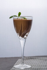 Chocolate cocktail with nuts and mint in a glass on a black background.