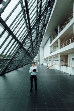 Male business professional working on digital tablet while standing in office corridor