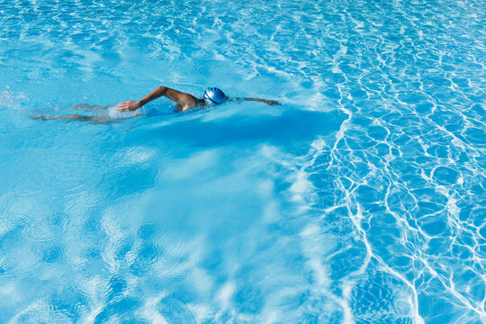 Woman swimming in clear blue swimming pool