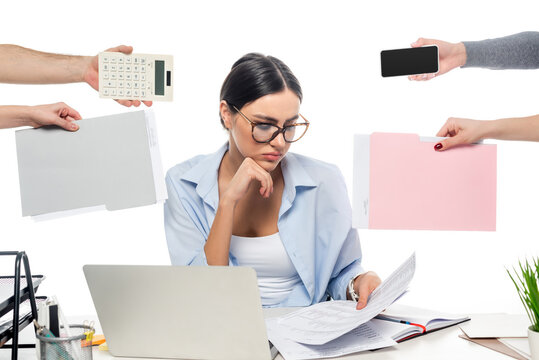 thoughtful businesswoman working near coworkers with documents, calculator and smartphone isolated on white.