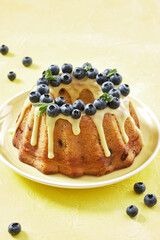 blueberry bundt cake with icing on a yellow background