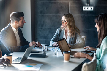 Businesswoman having discussion with team while sitting in meeting at office