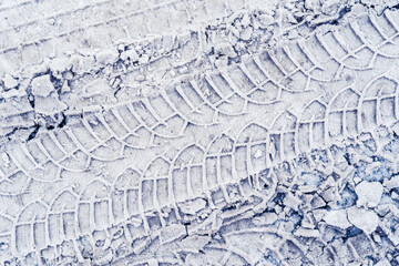 Parallel traces of car tires in the snow on the asphalt. Close up view from above