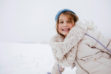 Playful girl smiling in warm clothing during winter