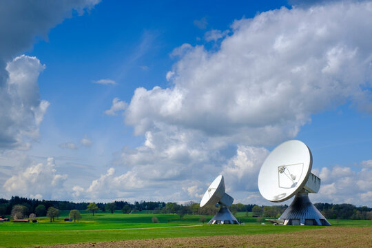 Germany, Bavaria, Raisting, Clouds over Cassegrain antennas standing in field