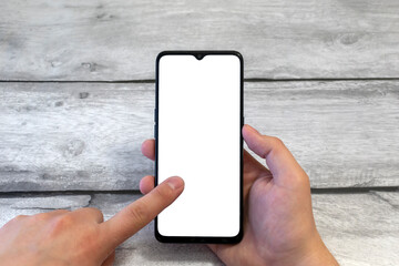 Hand using white smartphone screen on gray wooden surface background, close-up top view