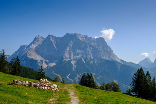 Firewood lying beside mountain footpath with Zugspitze in background