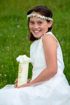 Cheerful girl in white dress holding candle on communion day