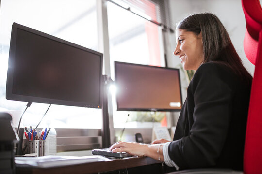 Smiling businesswoman using computer while sitting in warehouse office