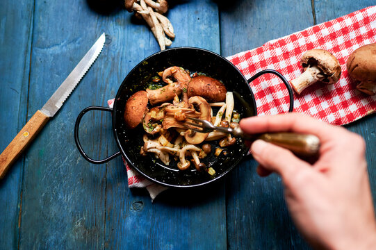 Hand Of Man Eating Pan Of Fried Mushrooms