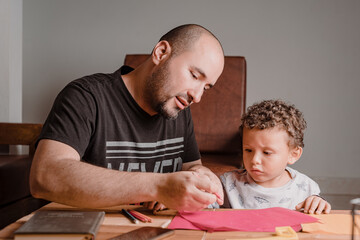 Dad teaching his son to take the pencil to write on the pad