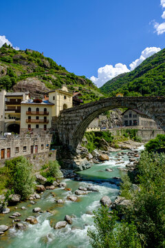 Italy, Pont-Saint-Martin, Town in Aosta Valley with Roman arch bridge stretching over river Lys in foreground