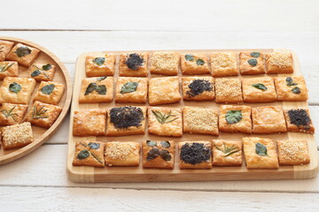 Homemade crackers decorated with herb leaves, sesame seeds, poppy seeds and salt