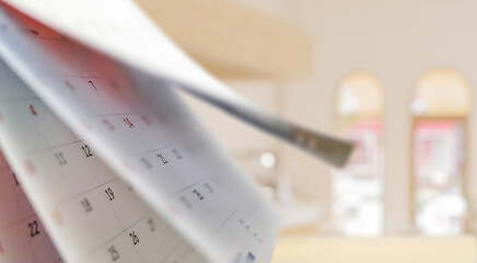 Close up white paper desk calendar with blurred bokeh background appointment and business meeting...