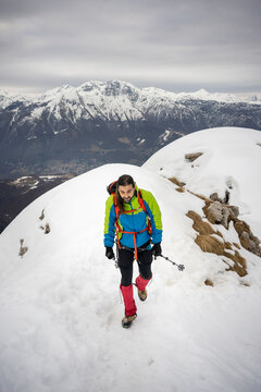 Alpinist walking with hiking pole on snowcapped mountain