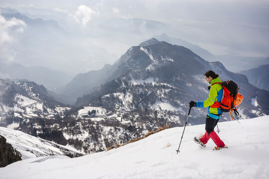 Male trekker with backpack and hiking pole walking on snowcapped mountain wearing crampon
