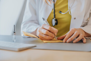 Doctor signing vaccination certificate while sitting by desk in office