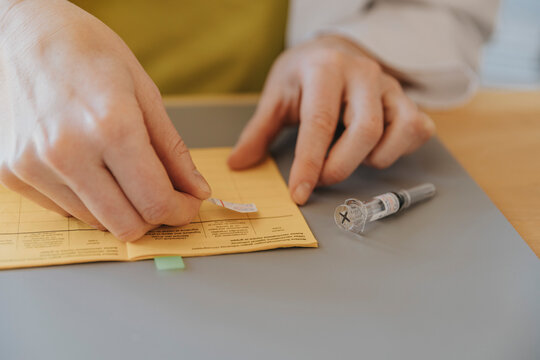 Doctor putting dose sticker on vaccination certificate while sitting at office