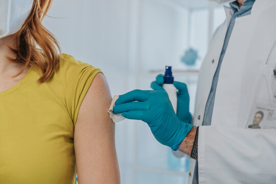 Doctor cleaning patient muscles while preparing for vaccination at examination room