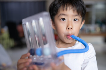 Thin boy uses a Tri-ball Incentive Spirometer for check his lung function.