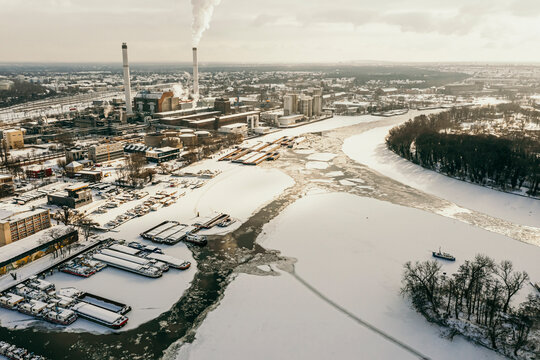 Germany, Berlin, Smoking power plant chimney towering over frozen Spree river