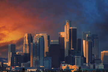 Downtown Los Angeles skyline at sunset, dramatic sky over city buildings.