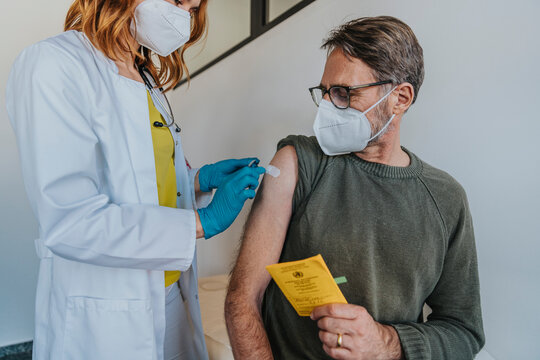 Female doctor putting adhesive bandage on patient arm while standing at examination room