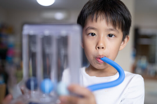 Thin boy uses a Tri-ball Incentive Spirometer for check his lung function.