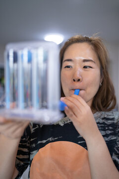 A woman uses a Tri-ball Incentive Spirometer for check his lung function.