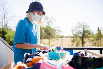 Young worker wearing protective face mask working on helmets during sunny day