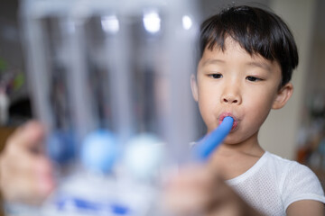 Thin boy uses a Tri-ball Incentive Spirometer for check his lung function.