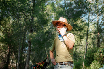 Old man in an orchard talking on the phone