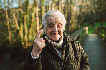 Elderly woman gesturing while standing on footbridge during winter
