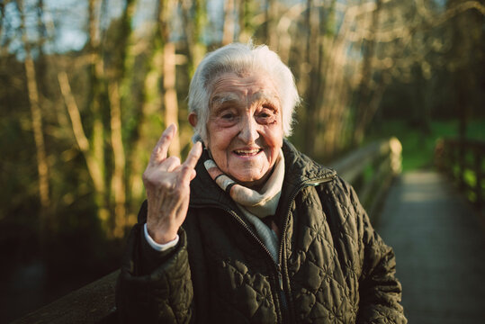 Cheerful elderly woman gesturing horn sign on sunny day