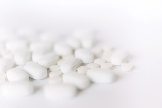 White pills on a white background. Oblong and round pills close-up. Healthcare and medicine.