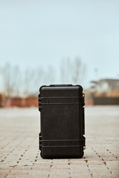 Black suitcase on footpath against clear sky