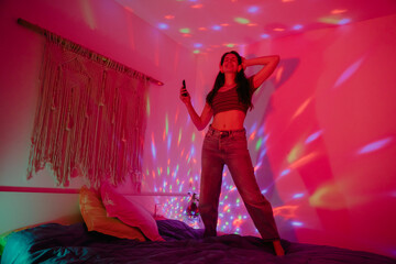 Cheerful woman dancing while partying in bedroom