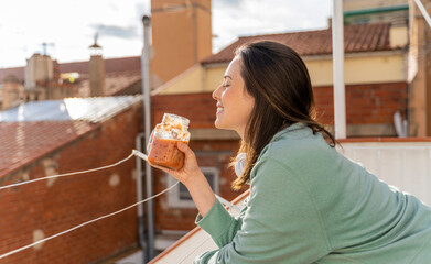 Smiling woman having fruit smoothie while standing in balcony
