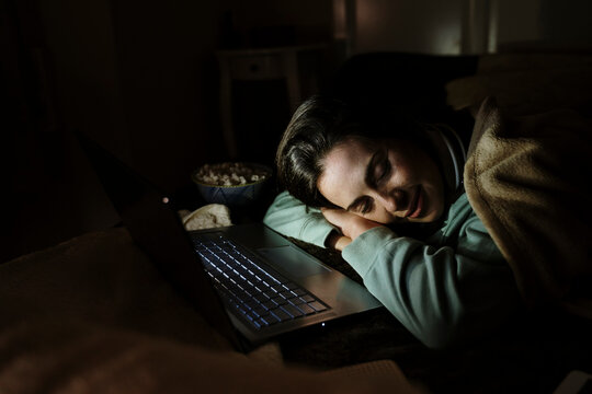 Woman with laptop relaxing while sleeping at home