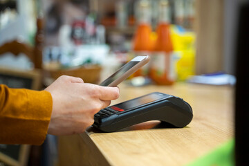 Woman using smart phone for contactless payment at grocery store checkout