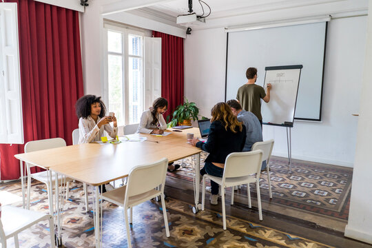 Male and female entrepreneurs discussing while sitting at conference table in office