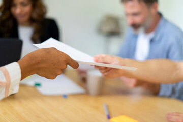 Coworkers passing document to each other at office