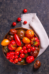 The harvest of assorted tomatoes. Colorful organic tomatoes on a large dish. Tomatoes different varieties. Top view