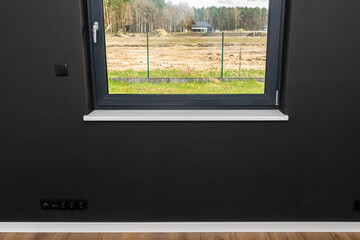 A large window in a room with black walls and fully open roller shutters.