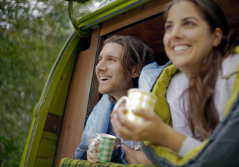 Couple having coffee in campervan while enjoying road trip