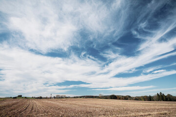 Barren agricultural field against blue sky at countryside
