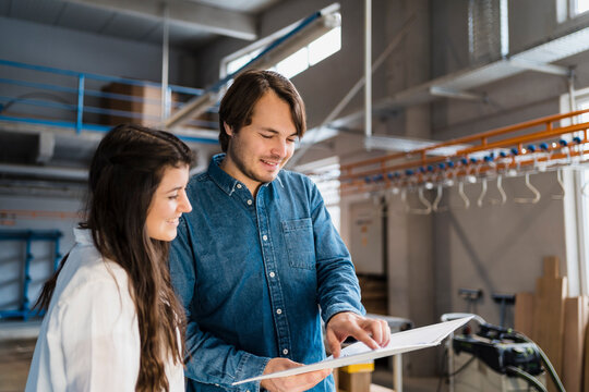 Smiling expertise pointing on file while working with colleague in industry